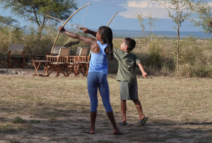 children practicing archery at camp during family safari