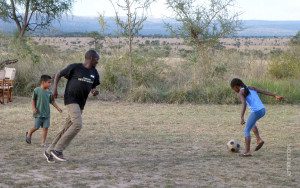 camp staff playing soccer with family guests
