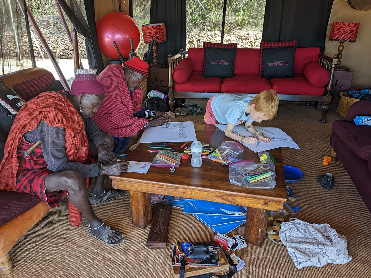 boy coloring with maasai at camp