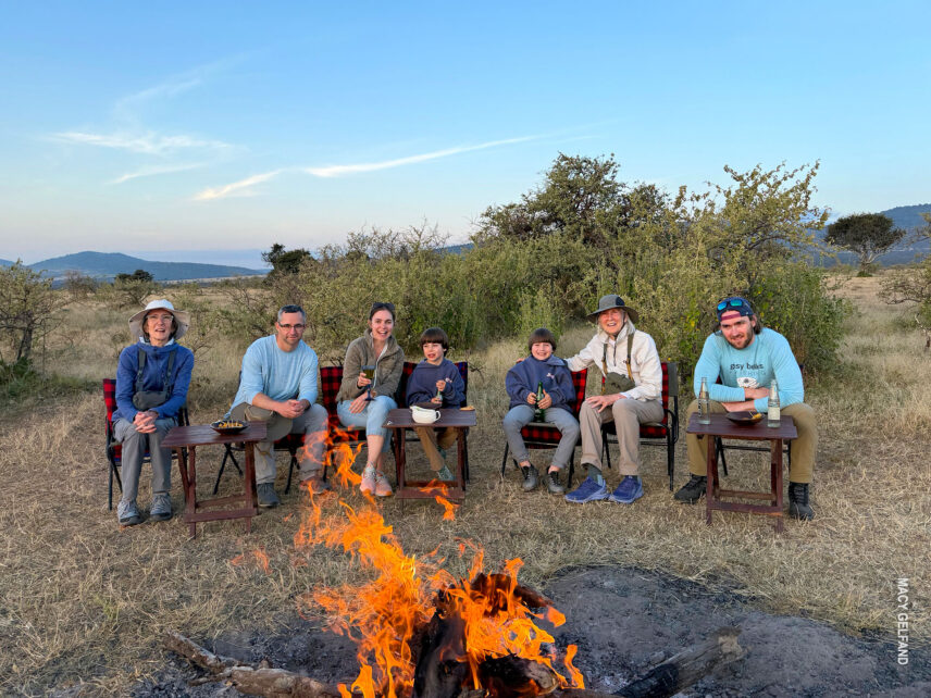multi generations sit around campfire at end of day at thomson serengeti nyumba camp during family safari