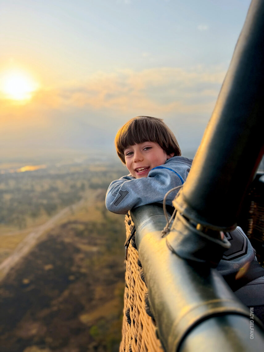 boy on family safari enjoying the hot air balloon flight at dawn over the serengeti