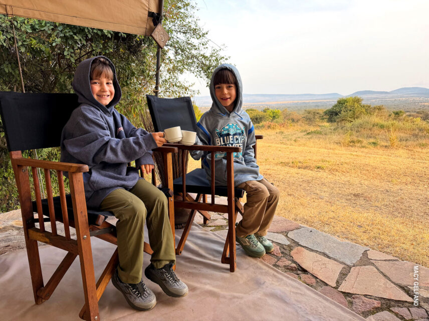 boys on veranda of their tent enjoying the morning hot chocolate delivery in eastern serengeti